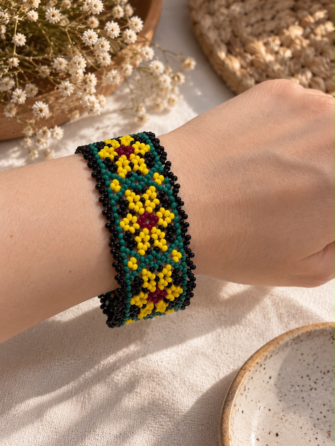 Beaded cuff with yellow flowers and teal accents against black